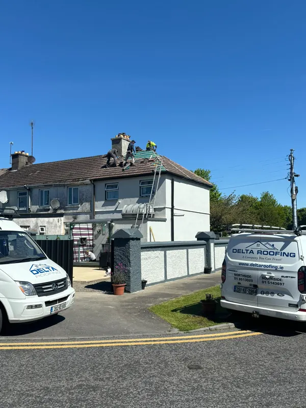 Crew on a terrace roof, vans below, Delta Roofing
